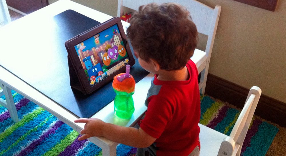 Niño pequeño viendo y escuchando música en una tablet