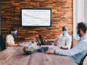Reunión en oficina con distancia y pantalla, relacionado con protocolo de casos y decisiones para reducir contagios
