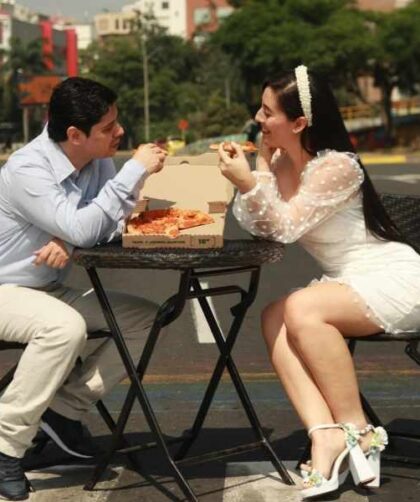 Dos personas conversando en una mesa al aire libre, en una cita con actitud seria y atenta.