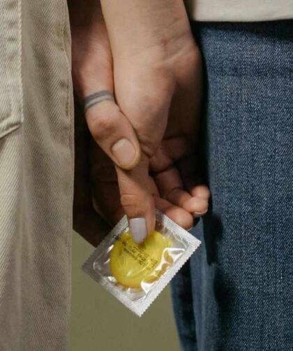 Persona sosteniendo un condón discretamente, relacionado con logística y negociación para usar condón