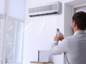Persona ajustando aire acondicionado, asociado a ventilación y reducción de riesgo de COVID en la oficina